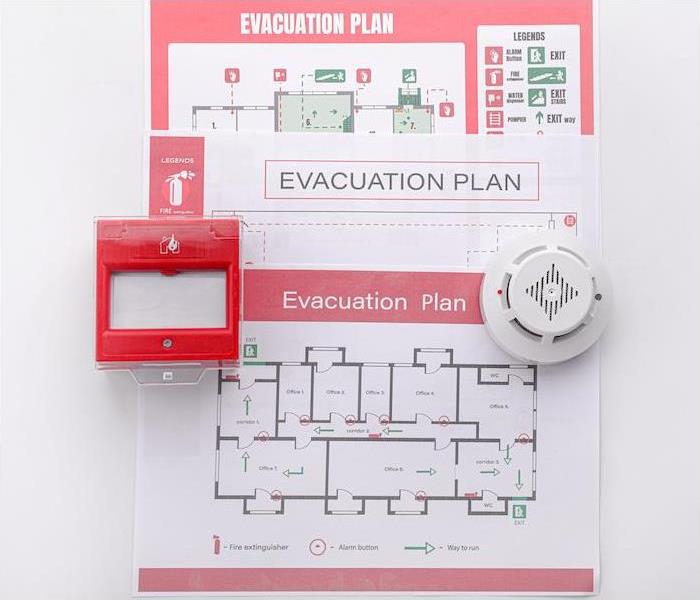 an evacuation plan and fire alarm hanging on a wall